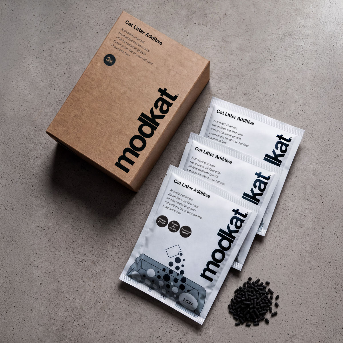 Modkat Cat litter Additive packaging on a concrete counter top with some bamboo charcoal granolas showing.