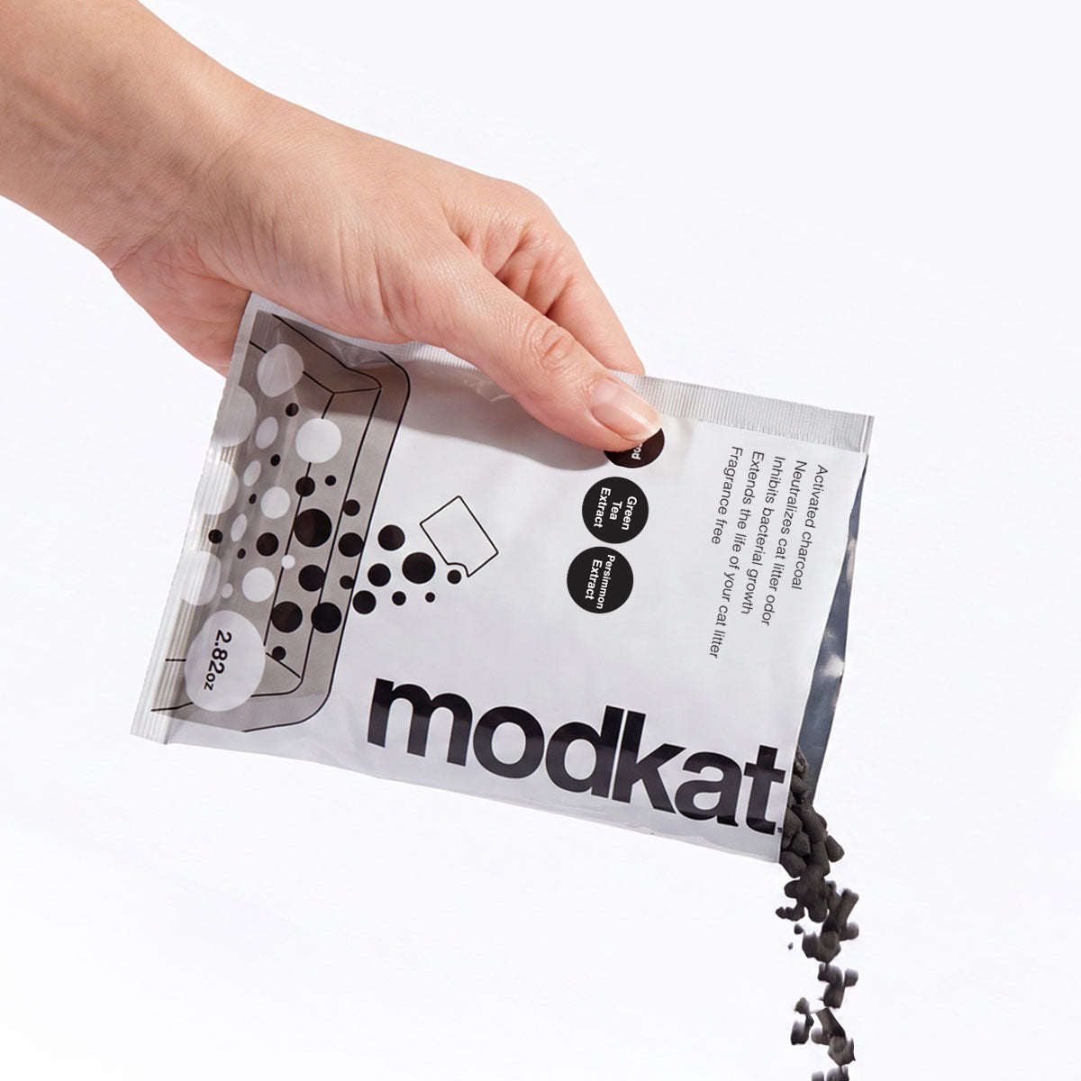 Hand pouring out Modkat Charcoal Bamboo Litter Additive.